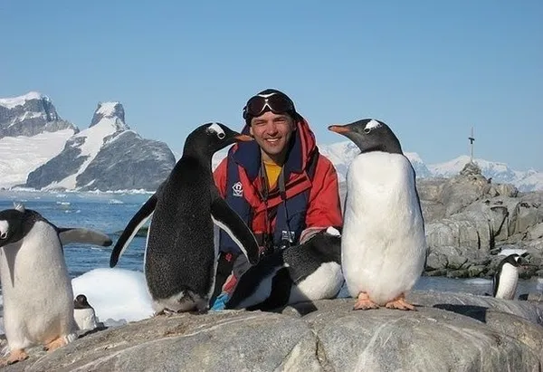 Улыбающийся мужчина рядом с пингвинами