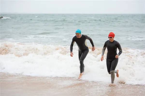 swimmers-in-wetsuits-running-in-sea-waves.jpg