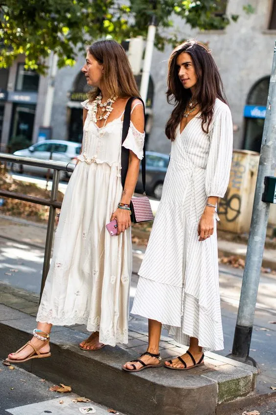 На девушках легкие белые свободные платья длины макси и босоножки с перепдетами на плоской подошве.