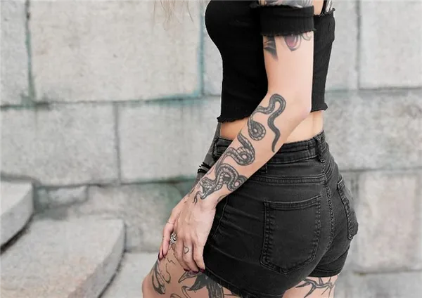 Девушка с шортах с татуировкой змеи на руке